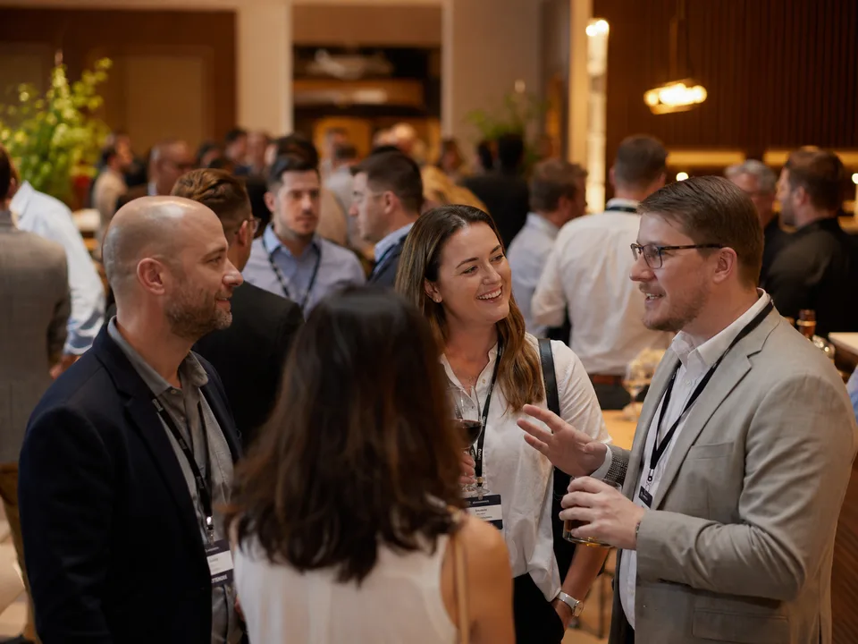 Warmly lit candid moment of attendees in conversation at a reception.