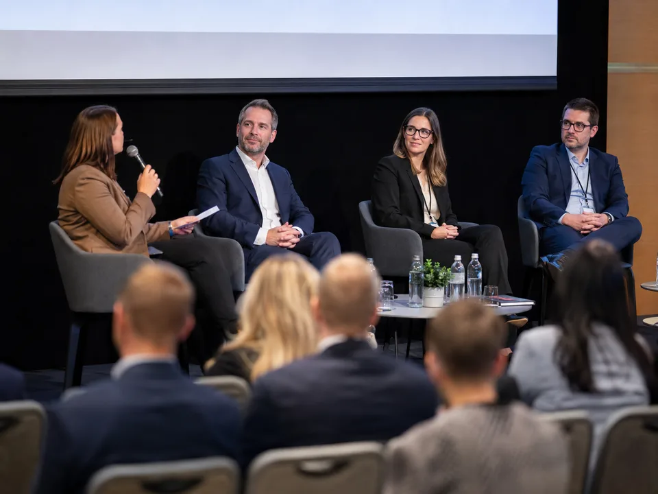 Moderator holding a microphone leading a four-person panel discussion.
