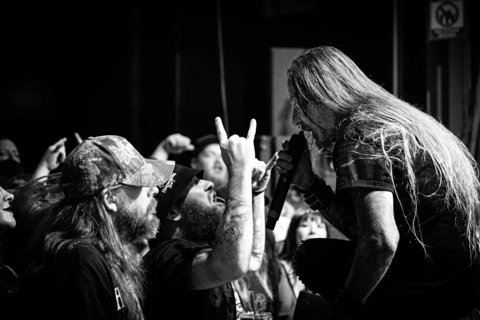 Vocalist leaning into the front row, singing face-to-face with fans, in black and white.